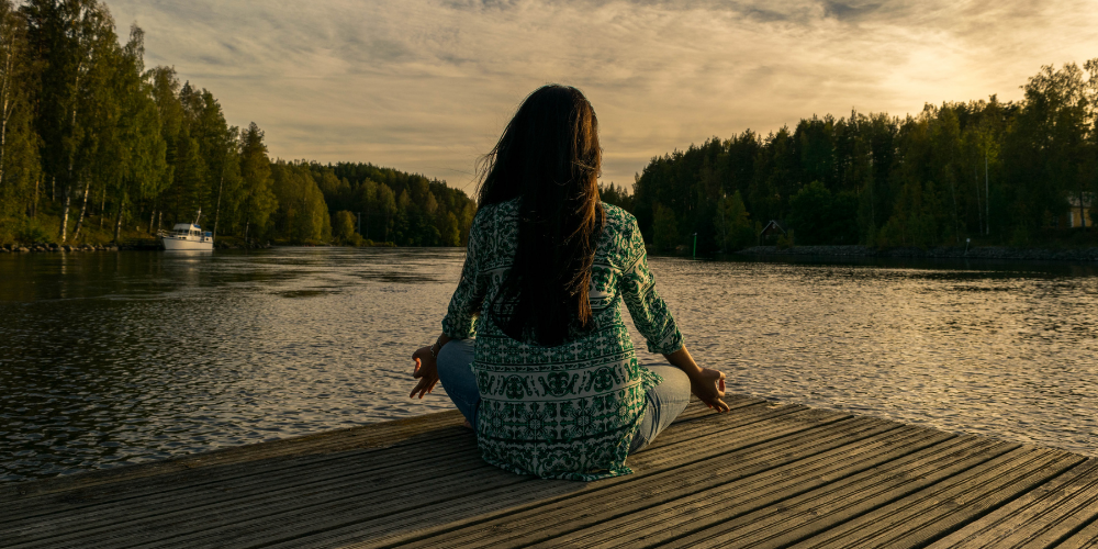 Donna che medita in riva ad un lago.